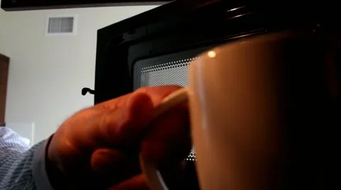 Man putting cup of coffee in microwave Stock Footage 44986197
