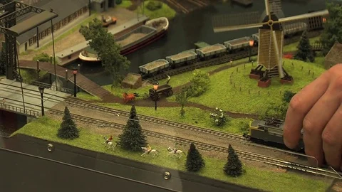 Man putting a derailed miniature train back on the tracks Stockbeeldmateriaal 75015324