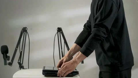A man putting down and opening a laptop with a podcast setup background Stock Footage 156022225