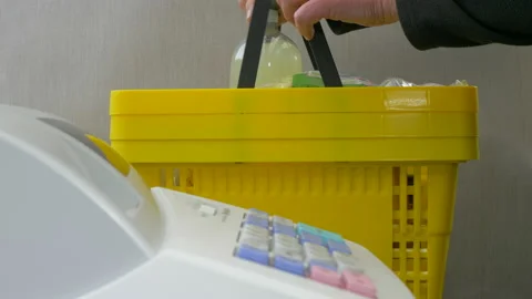 Man putting down a full yellow shopping basket next to a shop till. Stock Footage 141438783