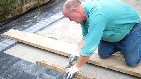 Man putting down stone pavers during a construction of a patio Stock-Footage 78390523