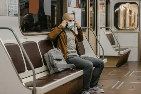 Man is putting on a face mask to avoid the spread of coronavirus in a subway  Stock Photos