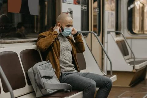 Man is putting on a face mask to avoid the spread of coronavirus in a subway  Stock Photos