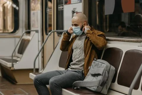 Man is putting on a face mask to avoid the spread of coronavirus in a subway  Stock Photos