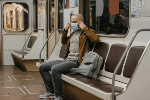 Man is putting on a face mask to avoid the spread of coronavirus in a subway  Stock Photos