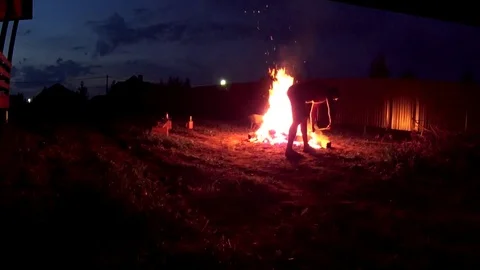 Man putting firewoods to a large bonfire, closeup shot Stock Footage 75247243