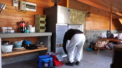 A man putting food in the refrigerator accommodating his things just arrived at Vídeos de archivo 199470570