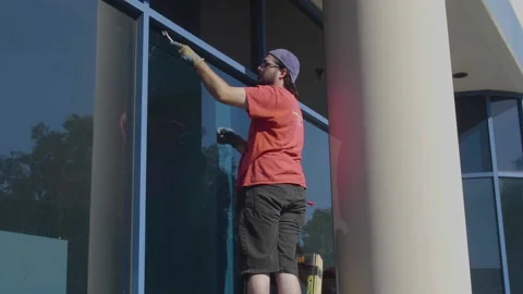 Man Putting on Glass Stops on Large Window Stock Footage 209289817