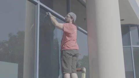 Man Putting on Glass Stops on Large Window - RAW Stock Footage 209289843