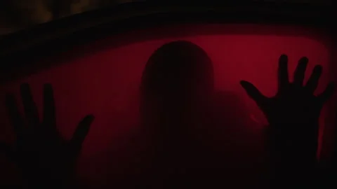 A man putting hands on window pane of in a parked car with red light in it 库存影片 259067627