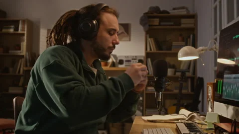 Man Putting on Headphones, Recording Harmonica in Home Music Studio Vidéo 337510471
