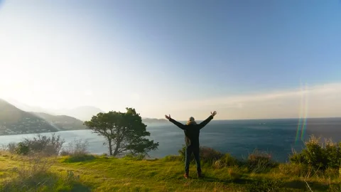A man putting his hands up and looking out to the sea at dawn. Montenegro. Stock Footage 273296308