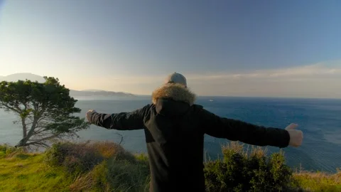 A man putting his hands up and looking out to the sea at dawn. Montenegro. Stock Footage 273296366