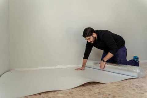Man putting insulation on the ground to put wooden laminate on the ground Stock Photos