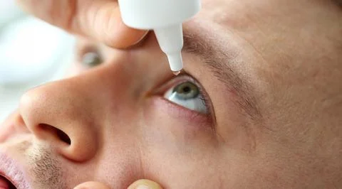 Man putting liquid drops in his eye solving vision problem Stock Photos