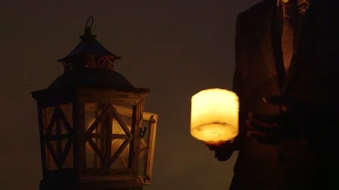Man Putting A Lit Candle Inside Of A Latern In The Evening Stock Footage 126701154