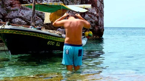 Man putting n diving mask and snorkel and jumping into sea next to the colorf Stock Footage 81309787