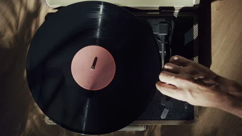 Man Putting Needle on Spinning Vinyl Record in the sunlight. Stock Footage 345395062
