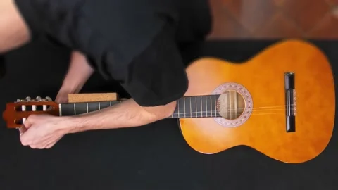 A man is putting on a new strings wire on a guitar. Video stock 141257301