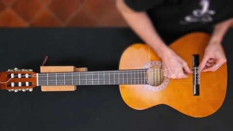 A man is putting on a new strings wire on a guitar. Video stock 141257976