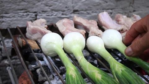 A man is putting onions on a grill with ribs Stock Footage