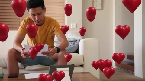 Man putting phone down tapping tablet marking docs while red hearts floating Stock Footage 333949736