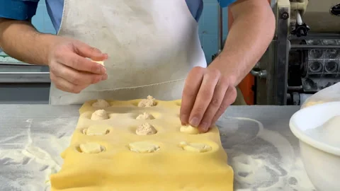 Man putting ravioli stuffing on pasta dough filling with cheese and closing it Stock Footage 138185356