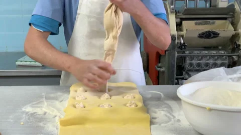 Man putting ravioli stuffing on pasta dough filling with cheese and closing it Stock Footage 138468420