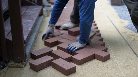 Man putting red brick pavers into place in a herringbone pattern on a bed of Stock Footage 82012160