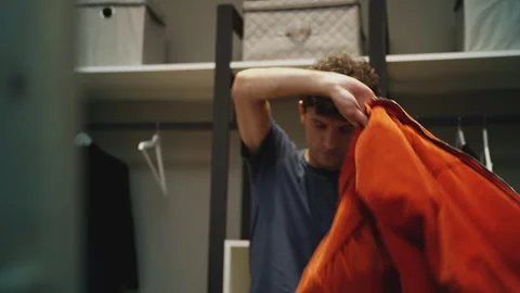 Man putting on stylish orange jacket in front of mirror, preparing for a date Stock Footage 337908110