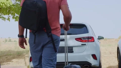 Man putting a suitcase into a car trunk before a road trip Stock Footage 341982906
