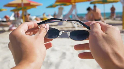 Man putting on sunglasses on the beach first-person view Stock Footage 65230554