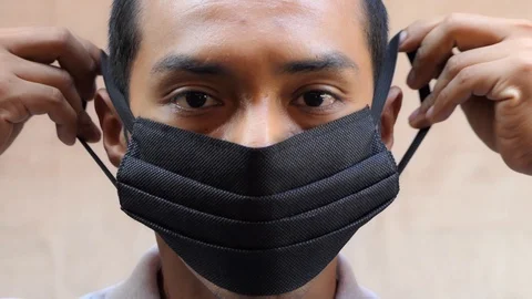 Man putting on surgical mask covering the lower half of his face. Stock Footage