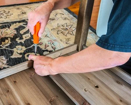 Man putting a table together using a screwdriver Stock Photos
