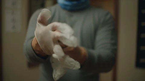 Man putting on &amp; taking off disposable vinyl gloves- Front view Stock Footage 128099229