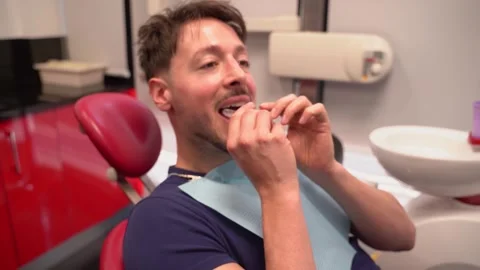Man putting at teeth aligner on in a mirror during a dental exam Stock Footage 307556100