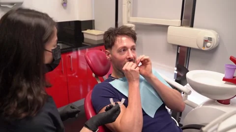 Man putting at teeth aligner on in a mirror during a dental exam Stock Footage 307556121