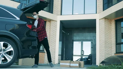 A man is putting together parcels at the doorstep of a building Stock Footage 133444623