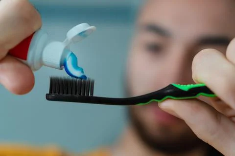 Man putting toothpaste on his toothbrush Stock Photos
