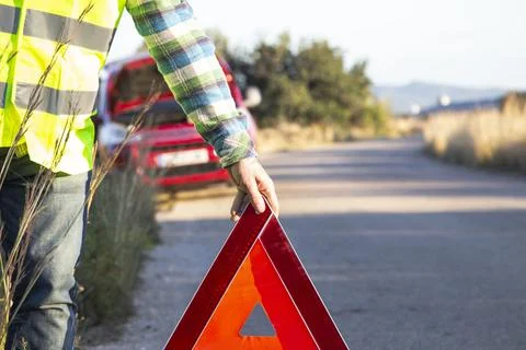 A man putting a warning triangle behind his car Stock Photos