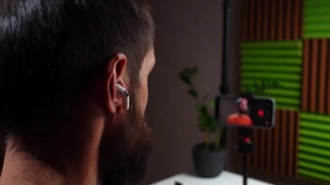 Man Putting on Wireless Earbud While Recording with a Smartphone Stock Footage 319832195