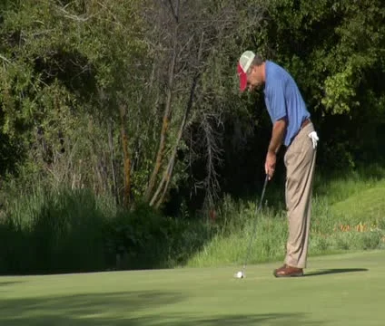 Man putts on golf green Stock Footage 21657626