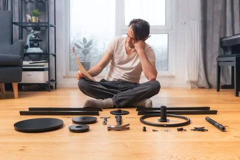 The man is puzzled studying the instructions for self-assembly of furniture. 스톡 사진