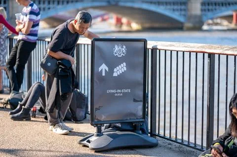 A man in The Queue looking at a sign for the Lying in State queue along the S Stock Photos