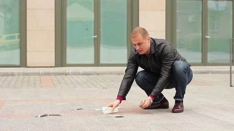 A man quickly picking up dollar bills from the floor. Concept of greed and greed Stock Footage 97470993
