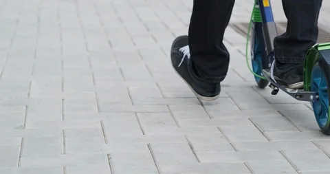 Man quickly rides scooter on clean slab of tiles on scooter on summer sunny day Stock Footage 115937679