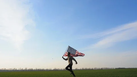A man quickly runs across the field with a large flag Stock Footage 97772689