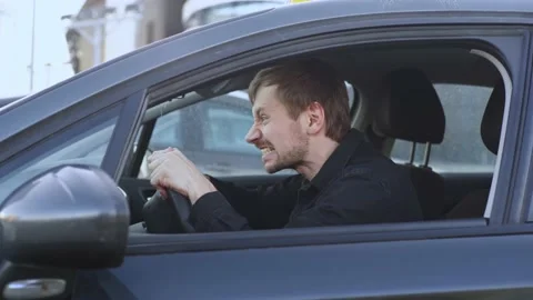 A man in a rage sitting in a car. Enraged driver hits the steering wheel. Stock Footage 176239043