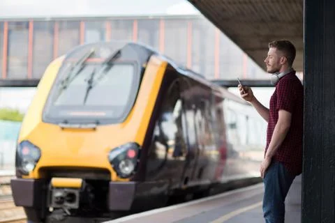 Man At Railway Station Using Mobile Phone On Platform Stock Photos