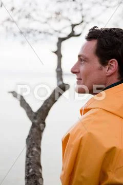 Man In Raincoat Looking On A Lake